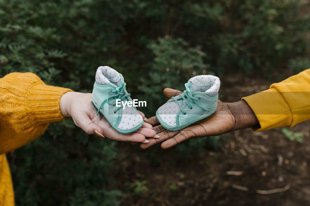 Close-up of couple holding baby booties at forest