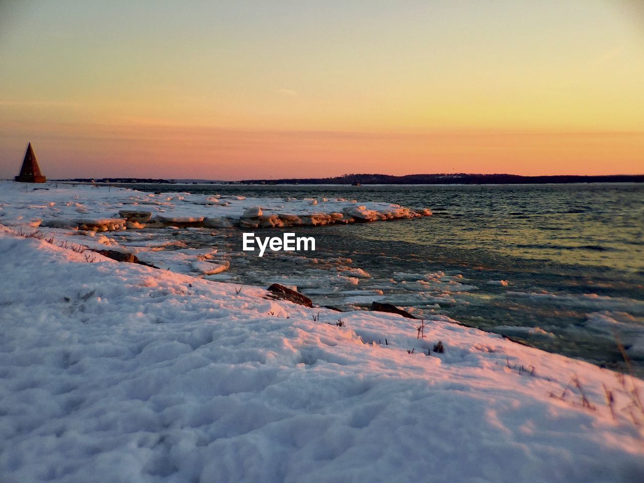 Scenic view of sea against orange sky during winter