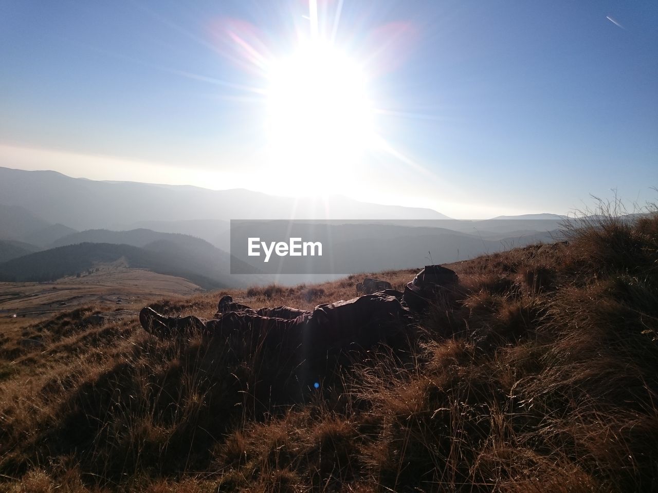 SUN SHINING THROUGH CLOUDS OVER MOUNTAINS