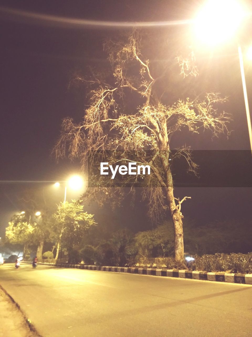 ILLUMINATED STREET LIGHT BY ROAD AGAINST SKY