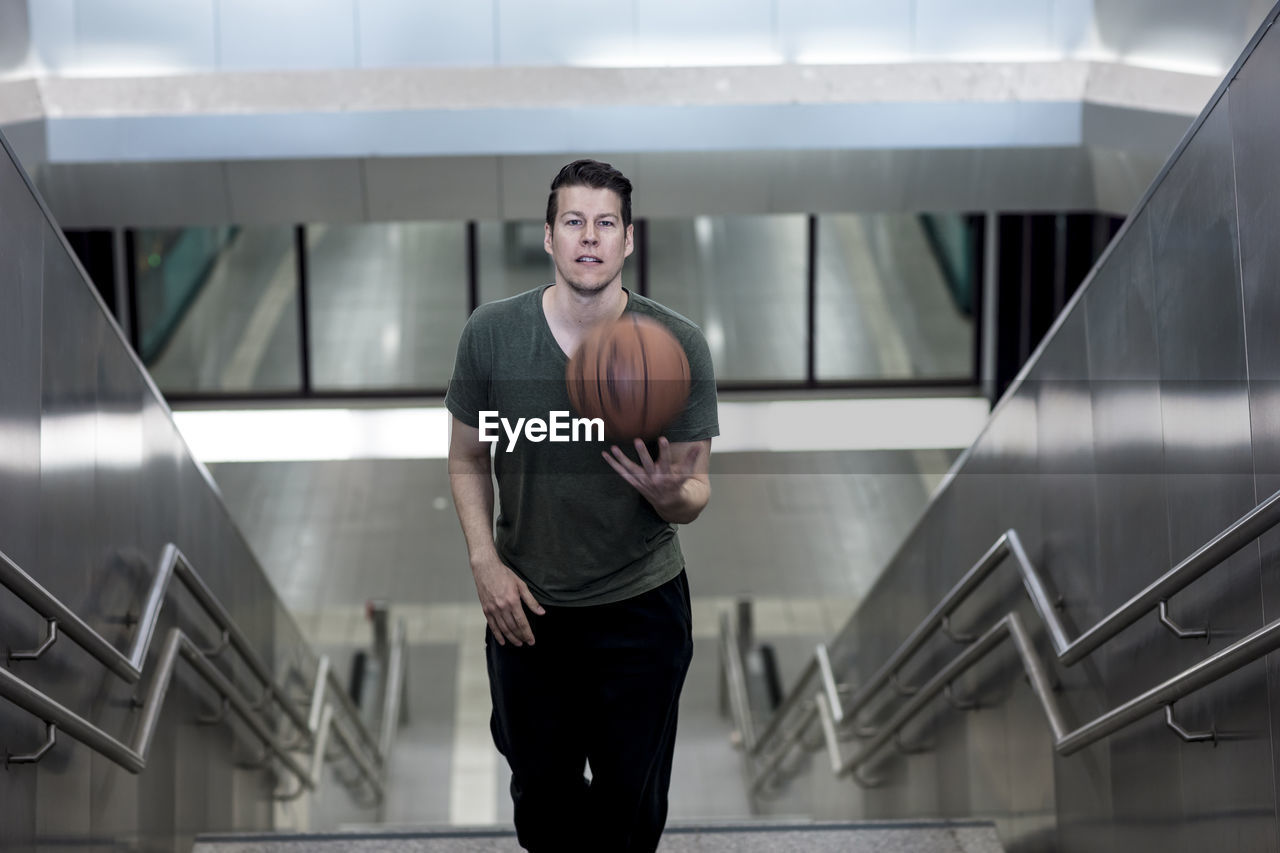 High angle portrait of young man with basketball moving up on steps