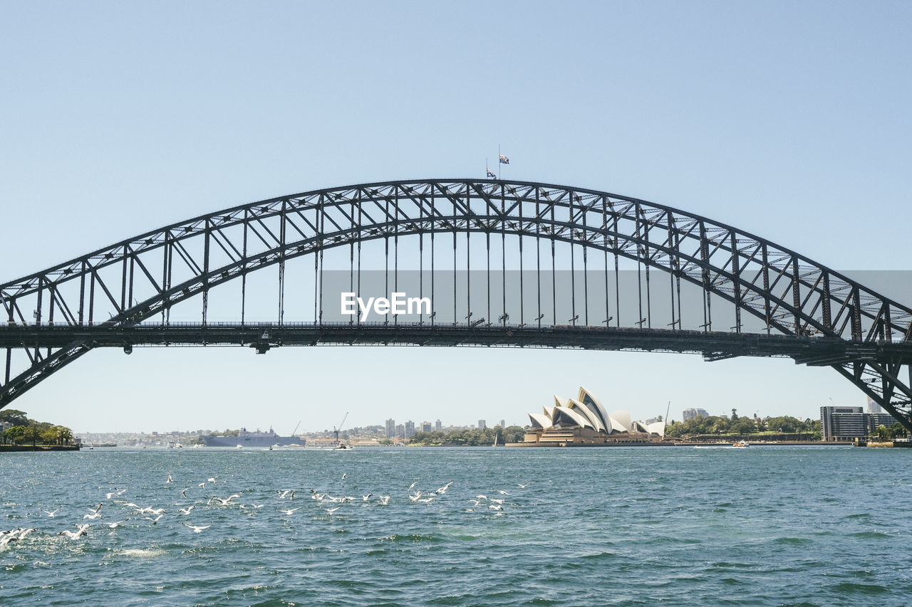 silhouette bridge over river against clear sky