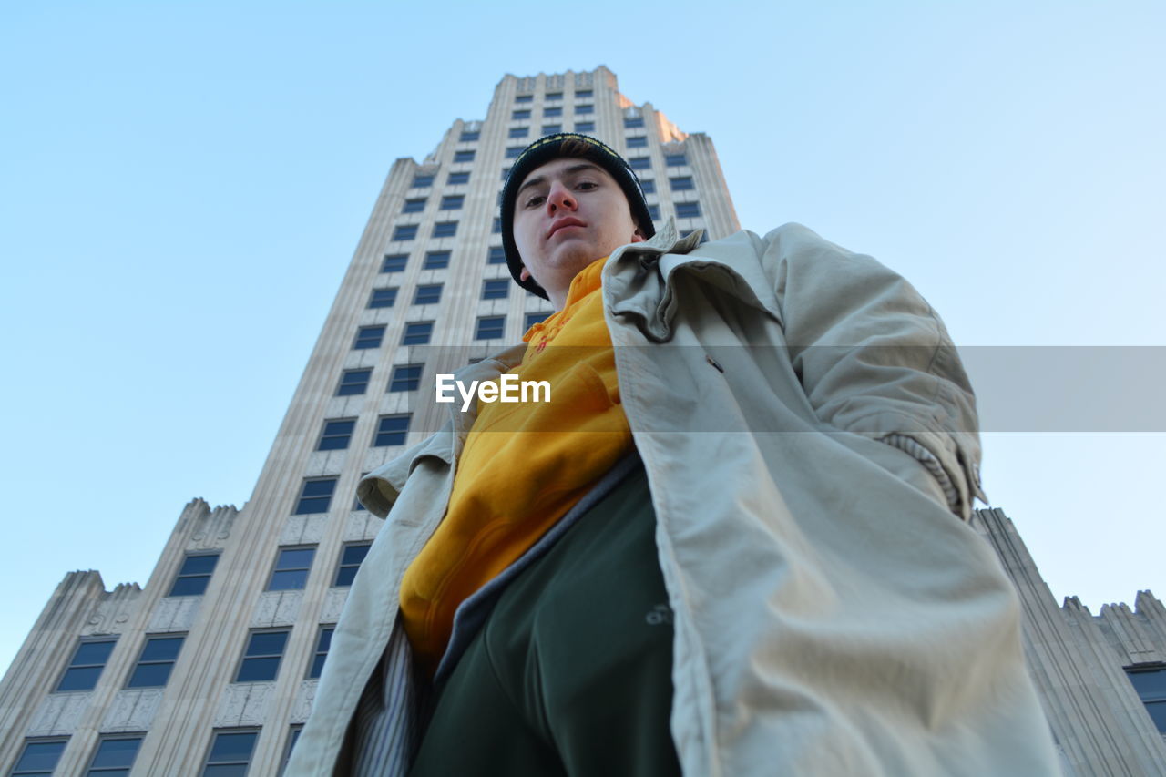 Low angle portrait of man standing against building in city