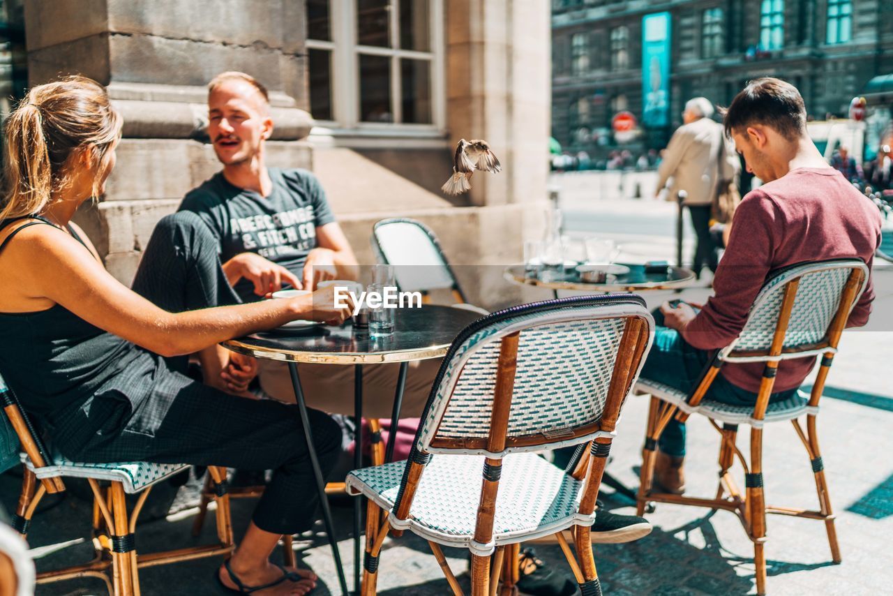 PEOPLE SITTING ON TABLE AT CAFE IN CITY IN TOWN