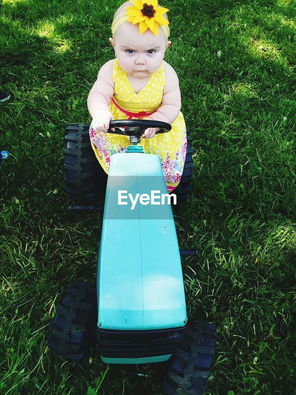 High angle view of cute baby girl driving toy car on grass