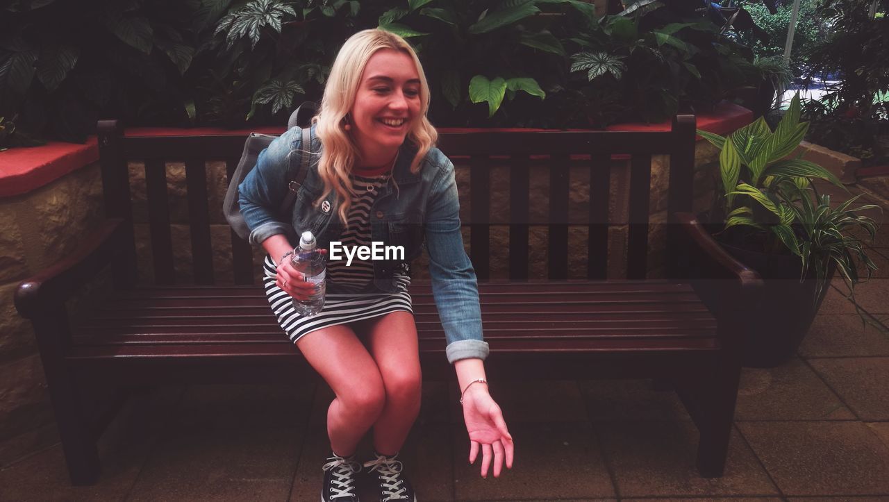 Smiling young woman sitting on bench