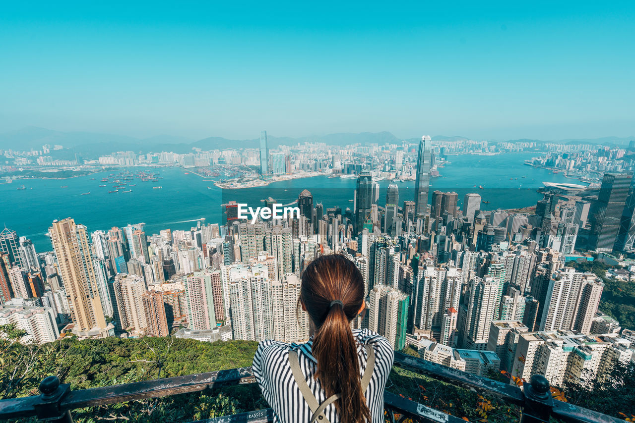 Rear view of woman over cityscape against sky