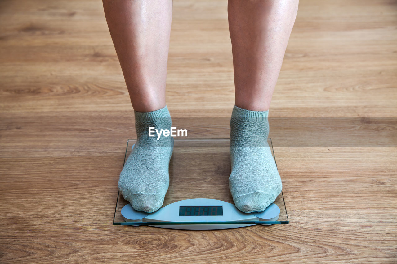 Low section of man standing on weight scale
