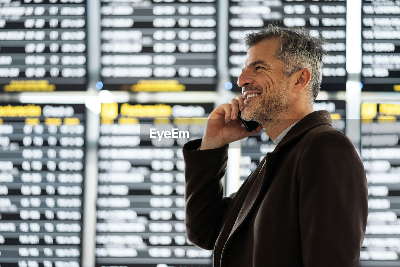 Smiling man talking on smart phone at airport