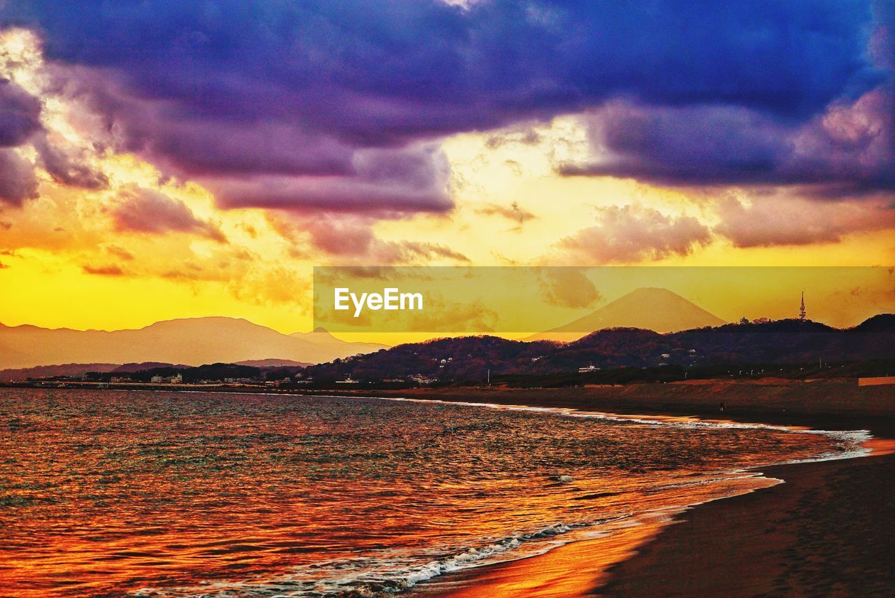 SCENIC VIEW OF BEACH AGAINST DRAMATIC SKY