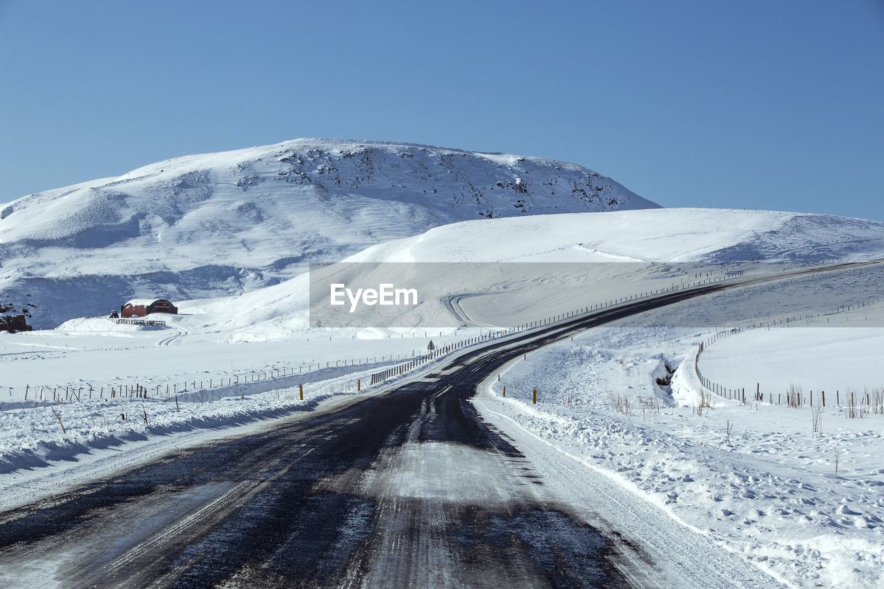 Snowy and slippery road with volcanic mountains in wintertime, iceland