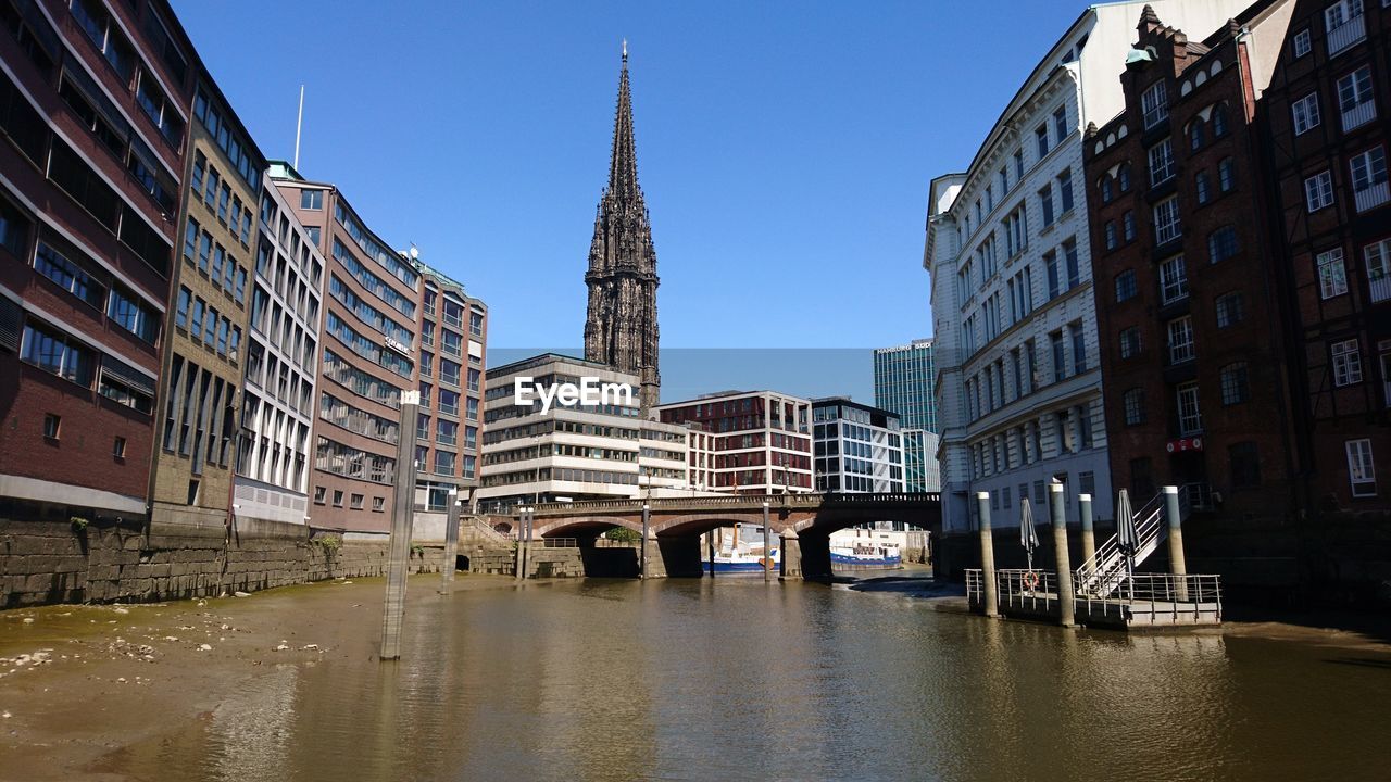 BRIDGE OVER CANAL AMIDST BUILDINGS IN CITY