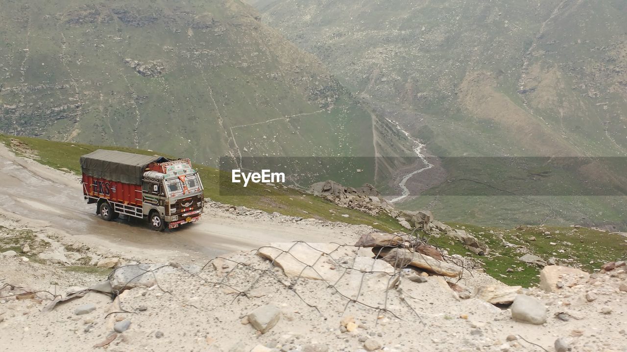 HIGH ANGLE VIEW OF VEHICLES ON ROAD AGAINST MOUNTAIN