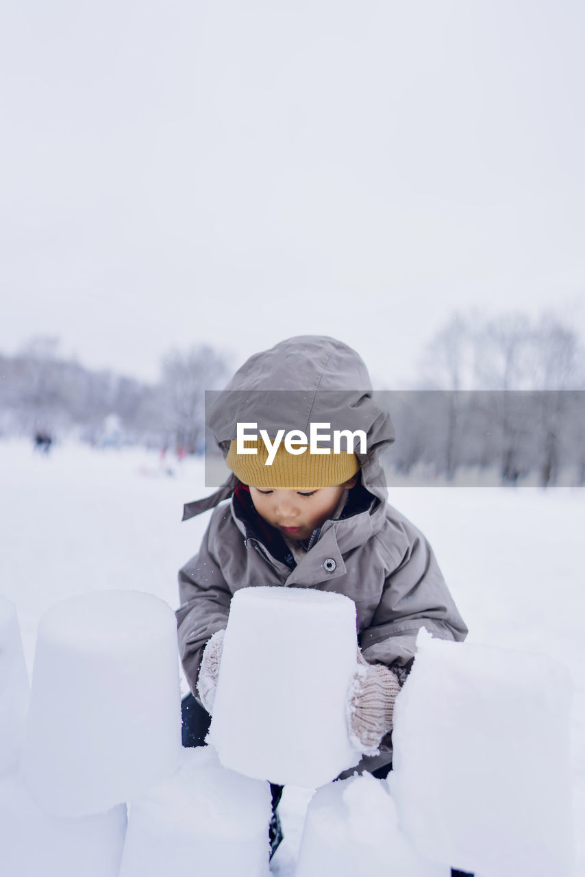 A boy playing ice bricks in a snowy winter