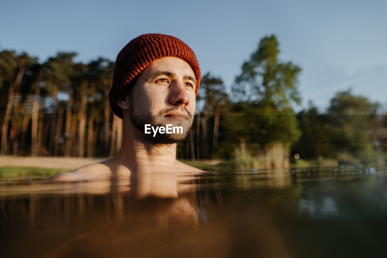 Portrait of young man soaks in the winter lake at morning. male person taking care of his heath