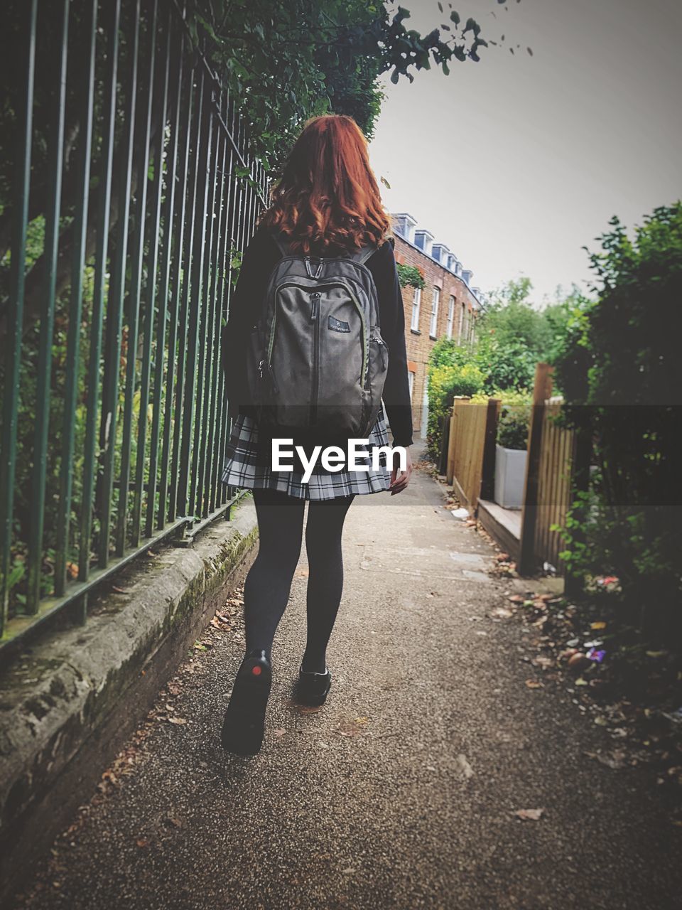 Rear view of girl walking by fence