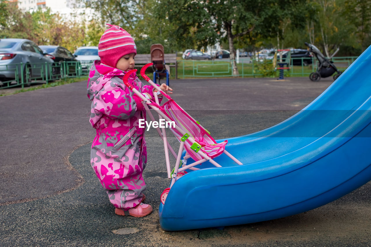 Low section of woman with pink slide in playground