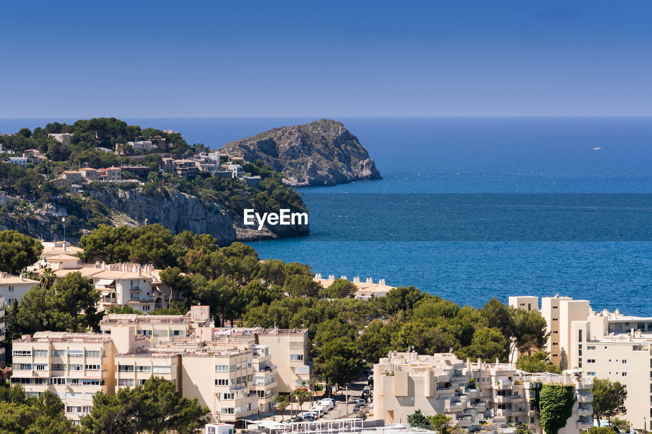 HIGH ANGLE VIEW OF TOWNSCAPE BY SEA AGAINST BLUE SKY