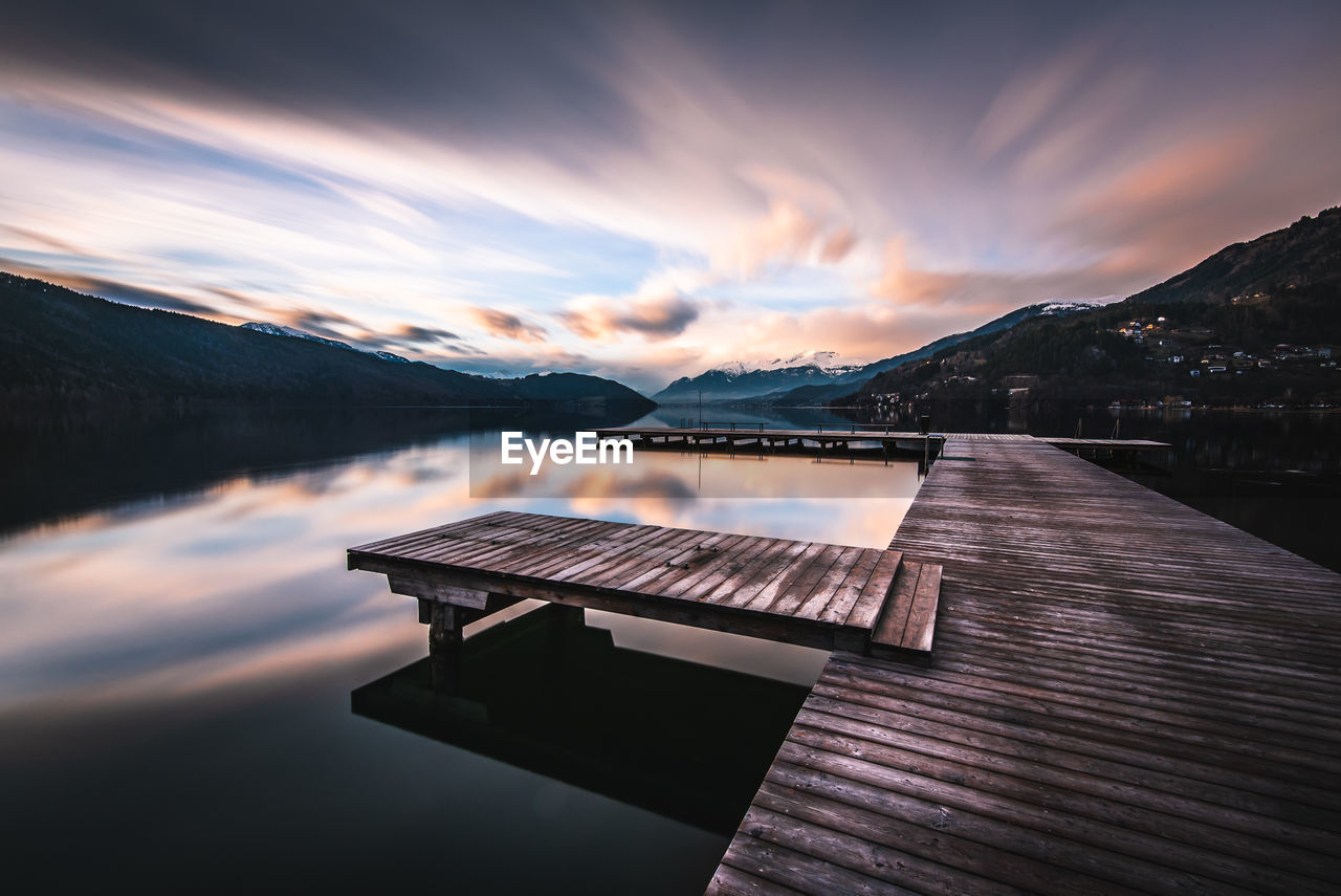 Pier over lake against sky during sunset