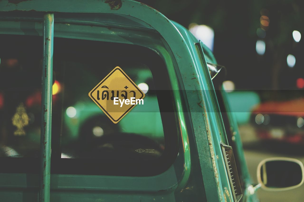 Close-up of yellow information sign on car at night