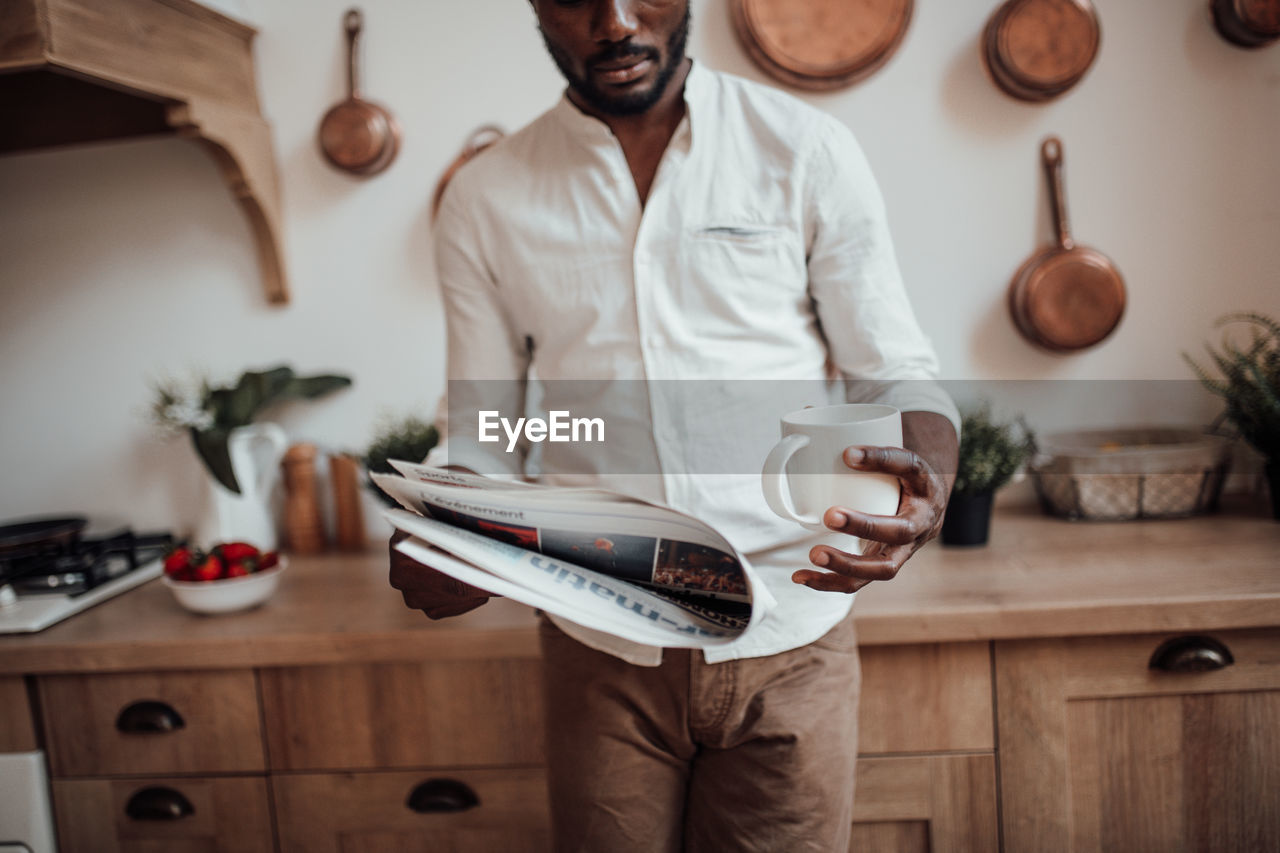 Midsection of man using laptop on table at home