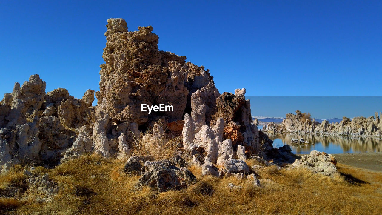 LOW ANGLE VIEW OF ROCKS AGAINST CLEAR BLUE SKY