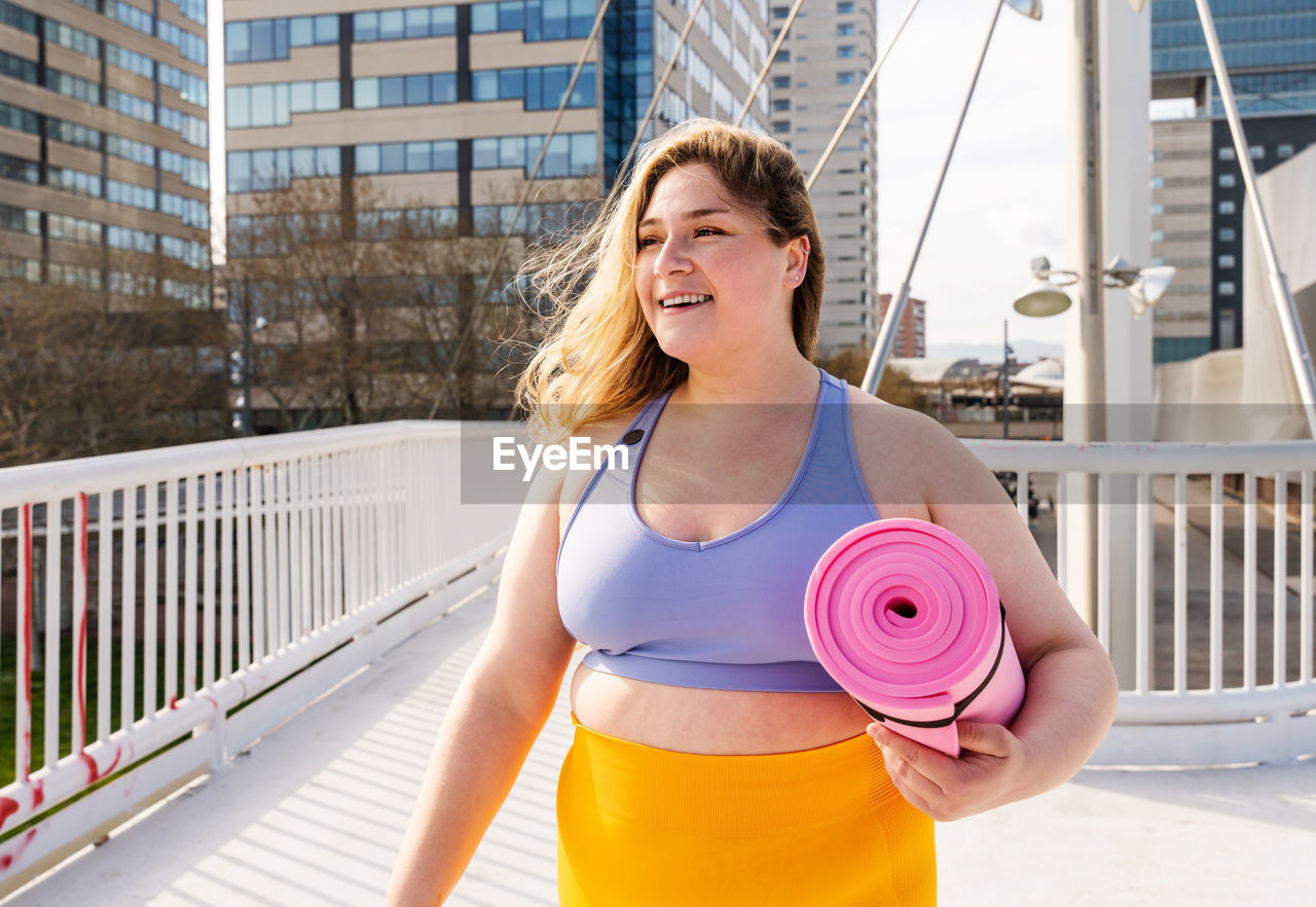 Young woman standing with yoga mat