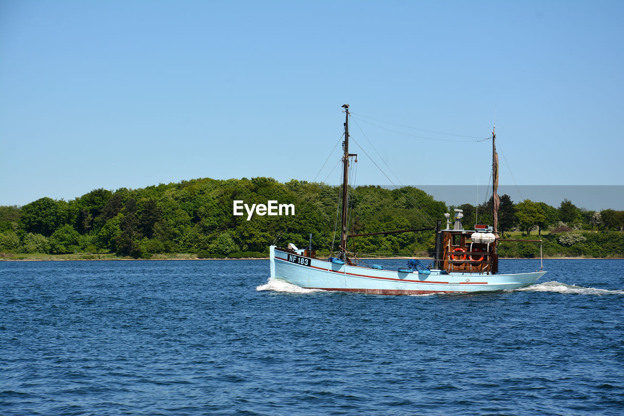 BOATS SAILING ON RIVER AGAINST CLEAR SKY