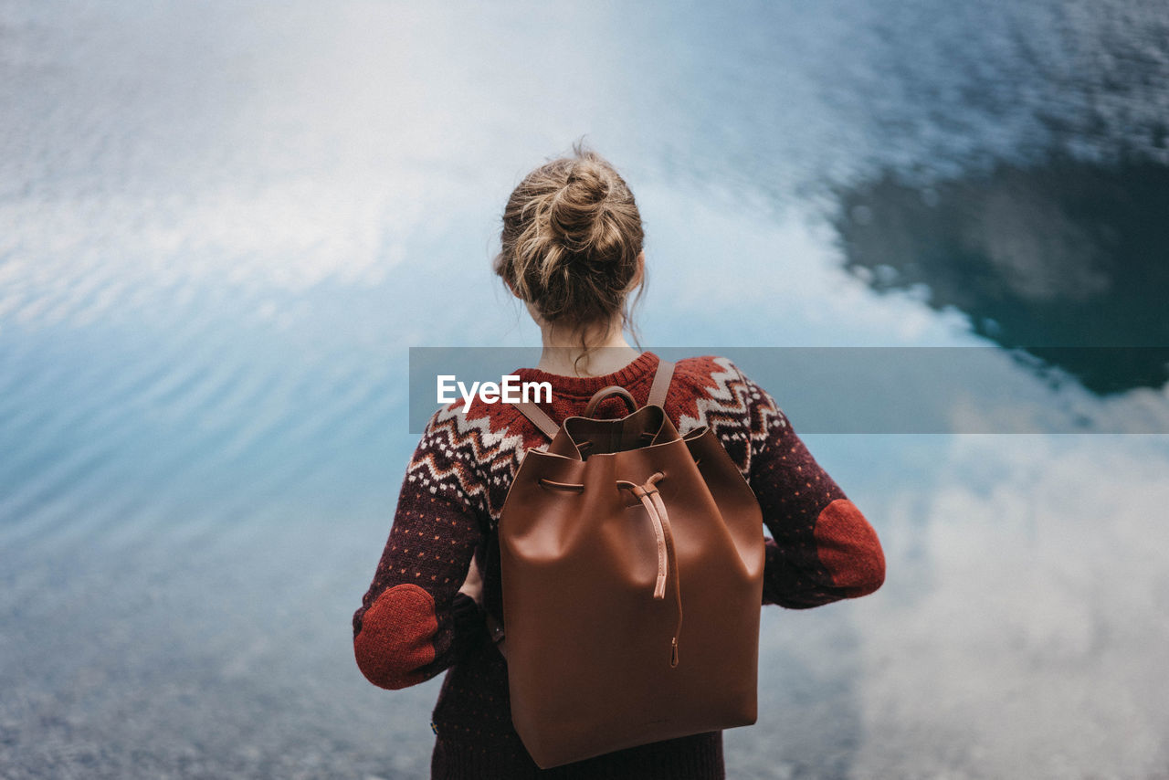 Rear view of woman with backpack standing by lake