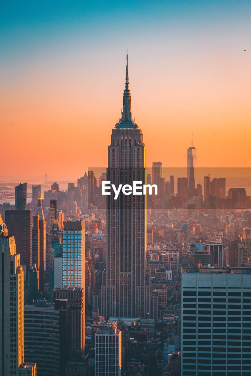 Empire state building in cityscape at sunset