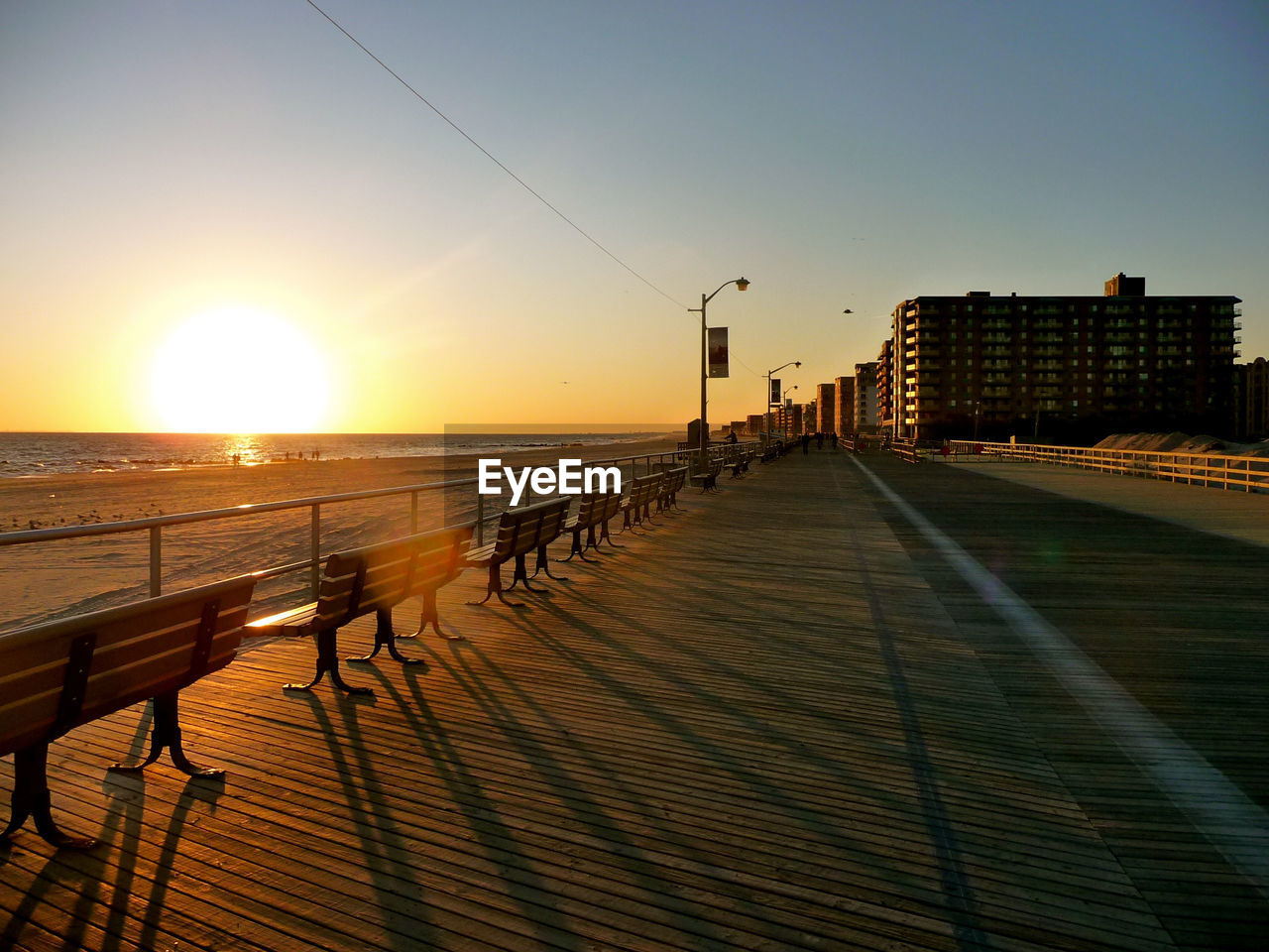 Promenade by building against sky during sunset