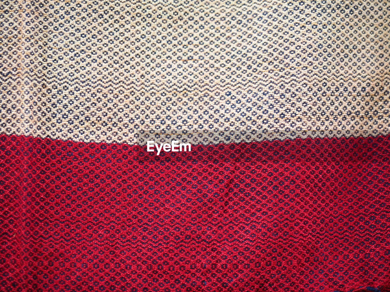 FULL FRAME SHOT OF RED PATTERN ON TEXTURED SURFACE