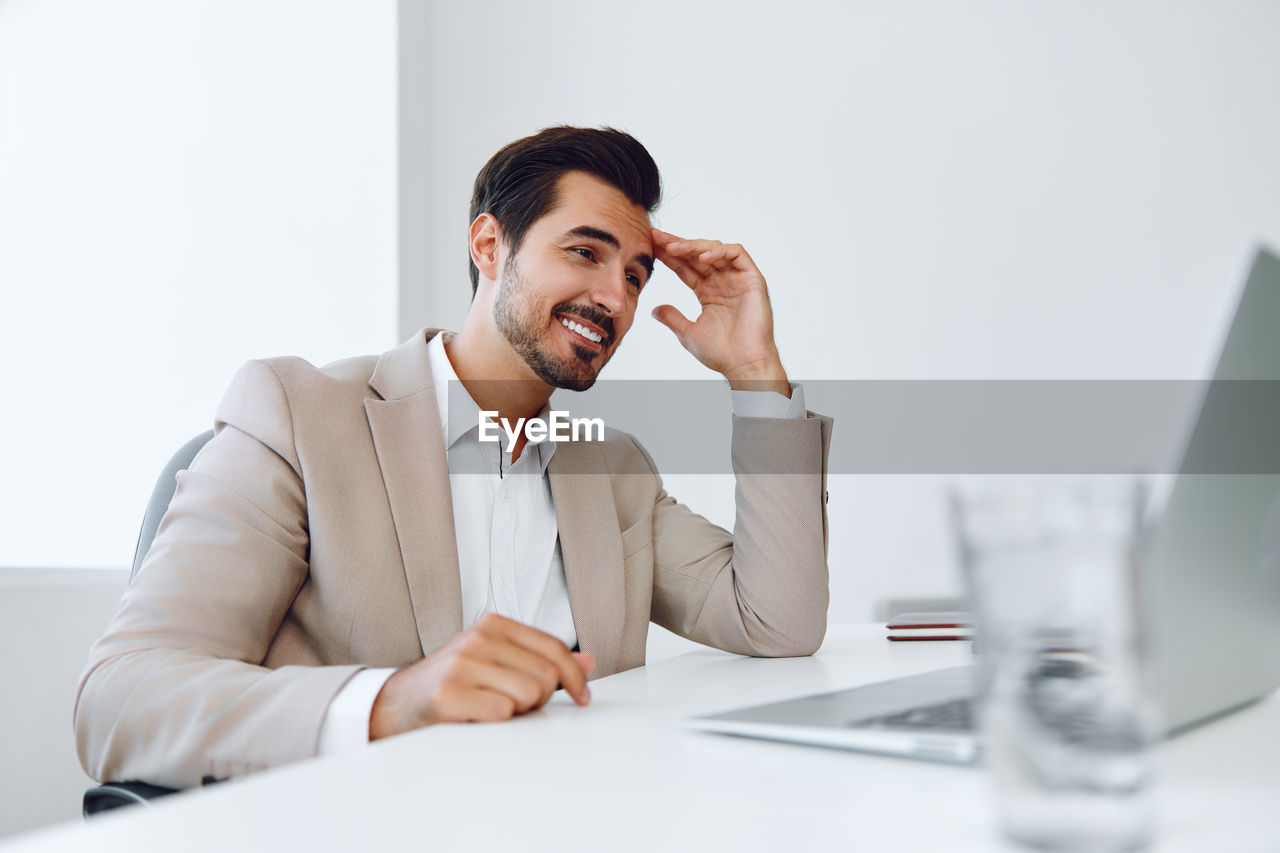 portrait of businessman using laptop while sitting on desk in office