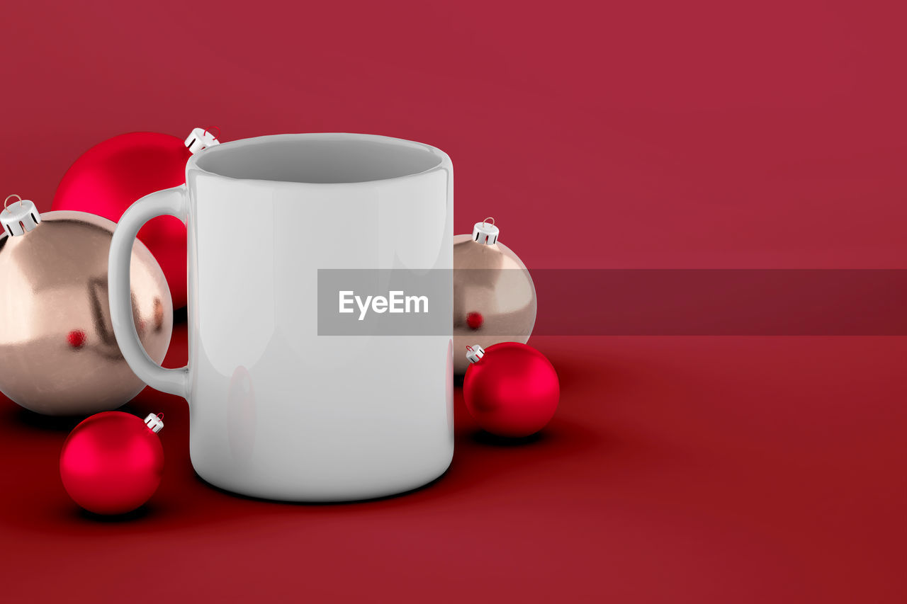 Cup of coffee and christmas ball mockup isolated on red background