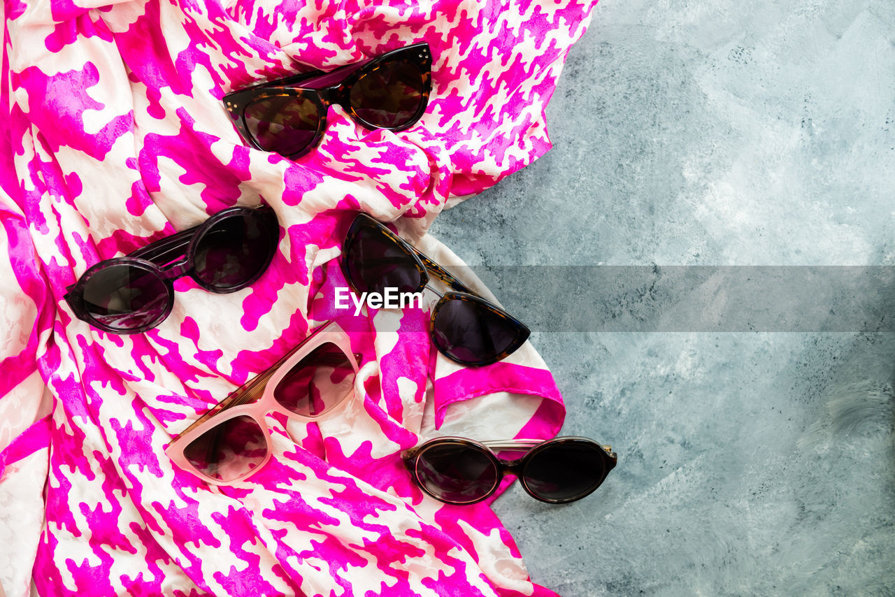 HIGH ANGLE VIEW OF SUNGLASSES AND SHOES ON PINK WATER
