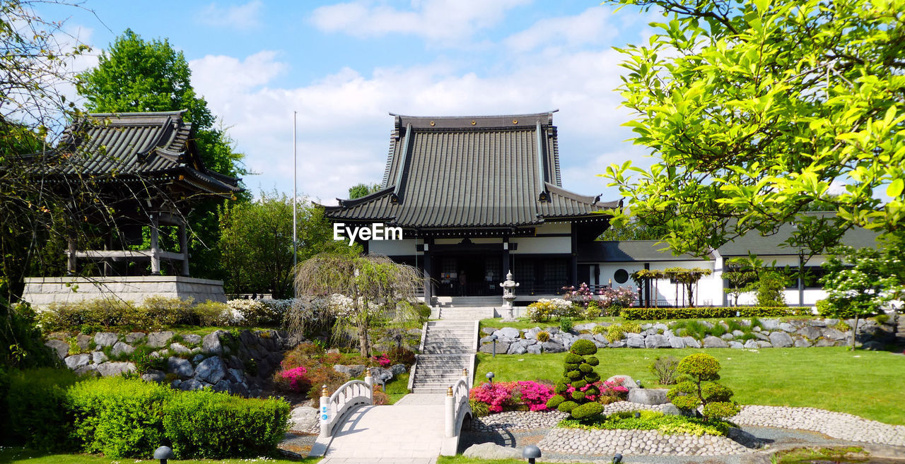 A view of temple, white bridge and staircase in japanese garden on a delightful sunny spring day