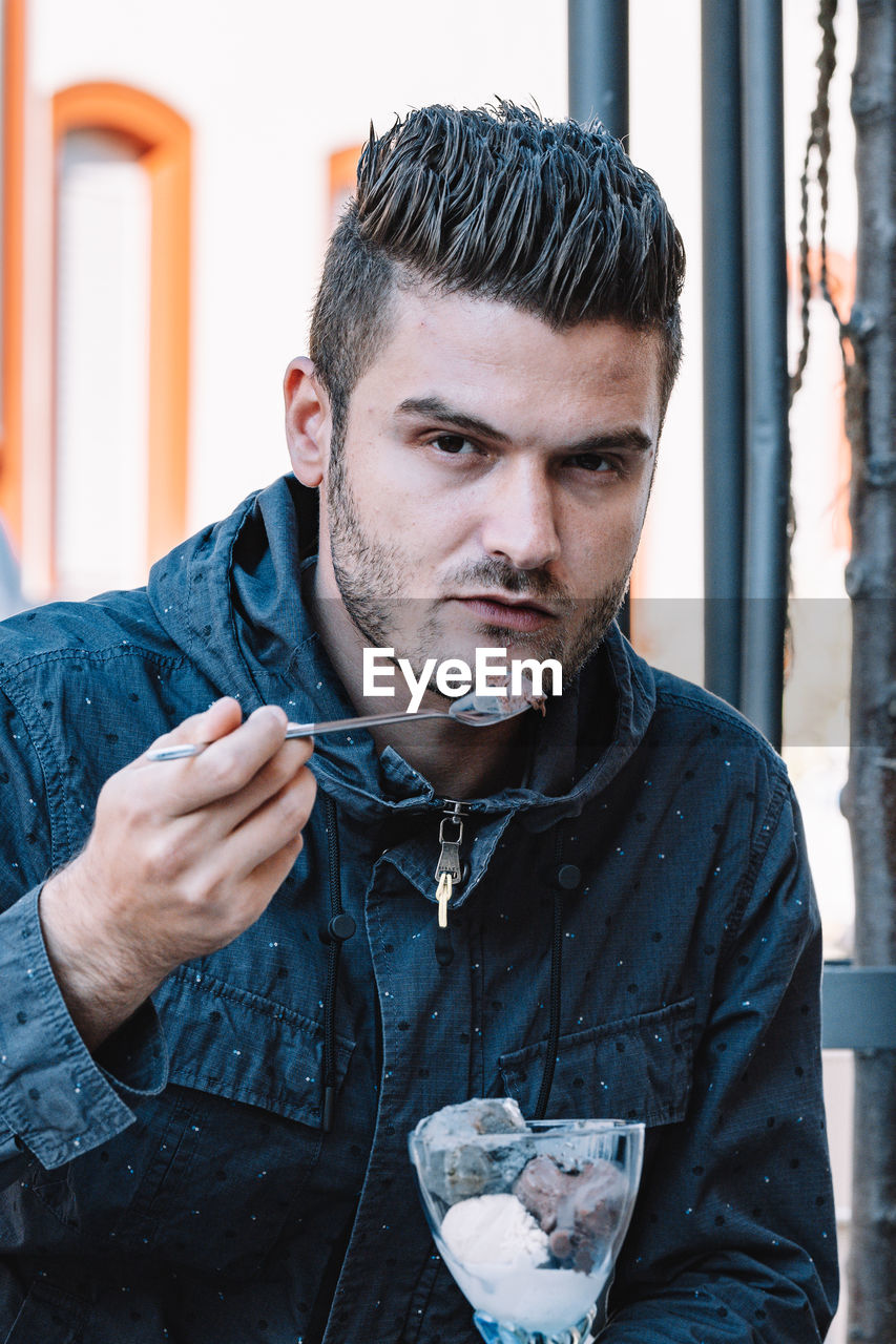 Portrait of young man eating ice cream outdoors