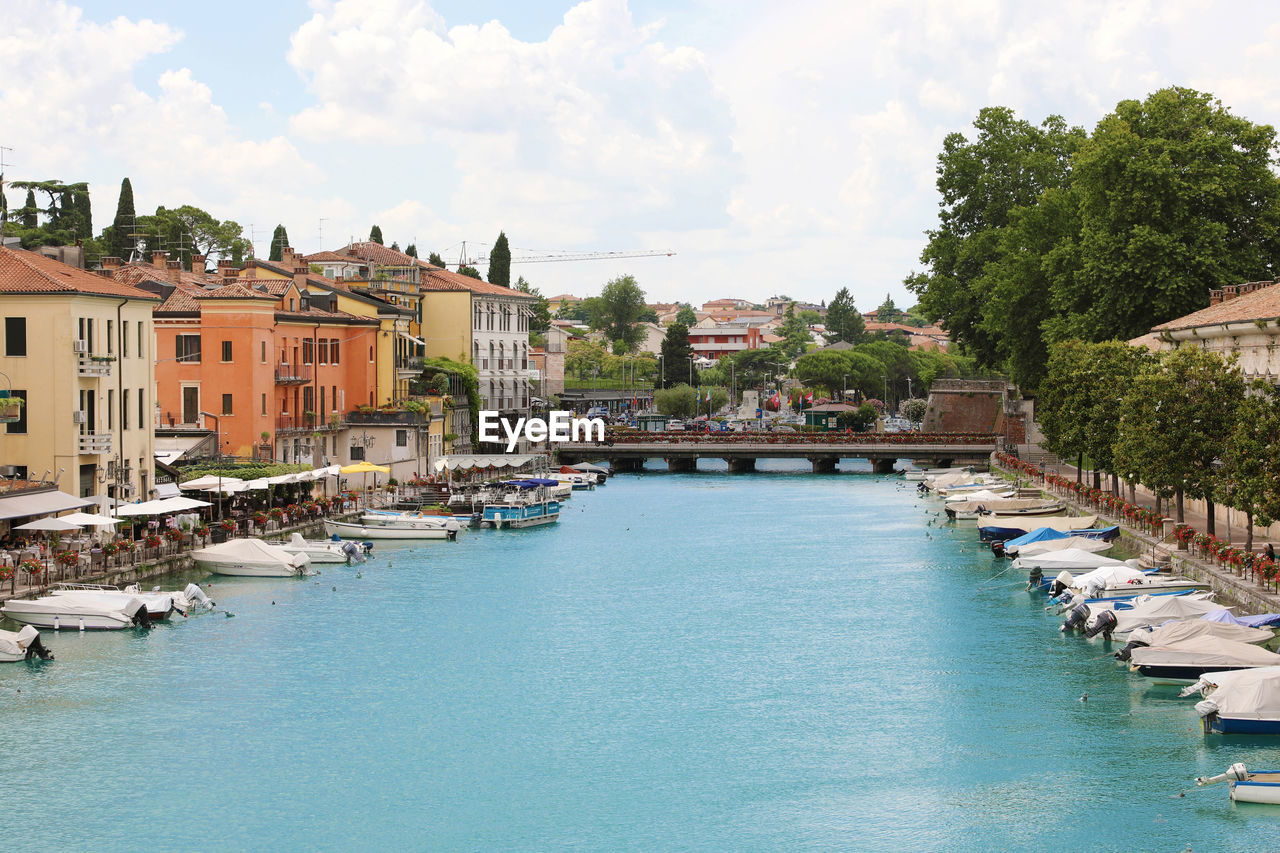 Peschiera del garda colorful and flowered harbor with boats moored lake garda, italy