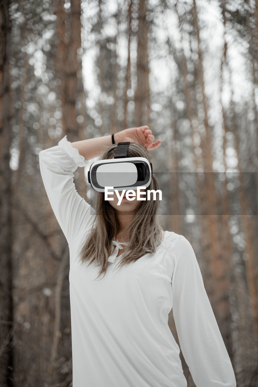 Woman wearing virtual reality simulator against trees outdoors