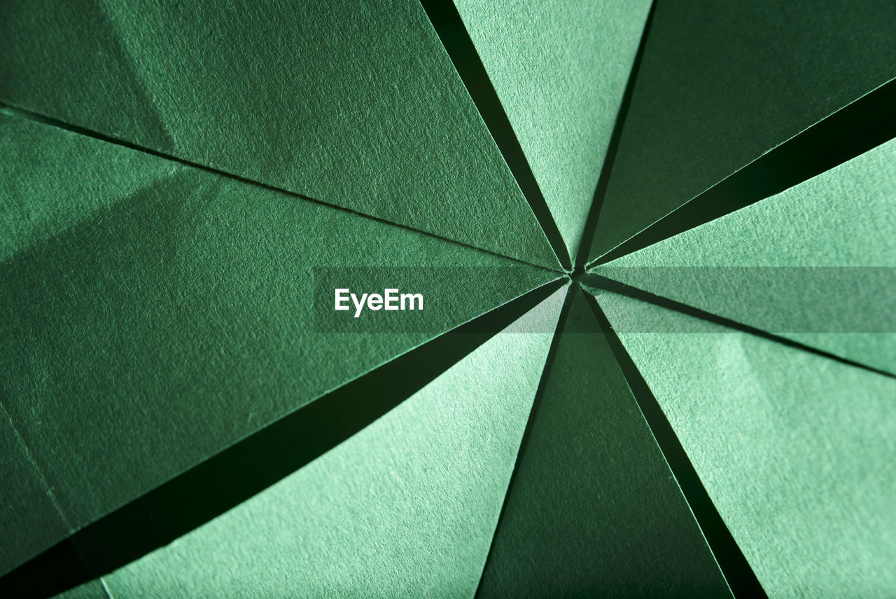 Abstract radial green background of folded textured paper, origami