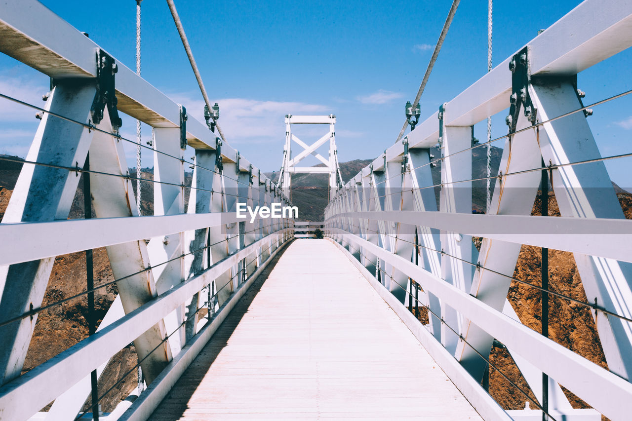 View of footbridge against blue sky