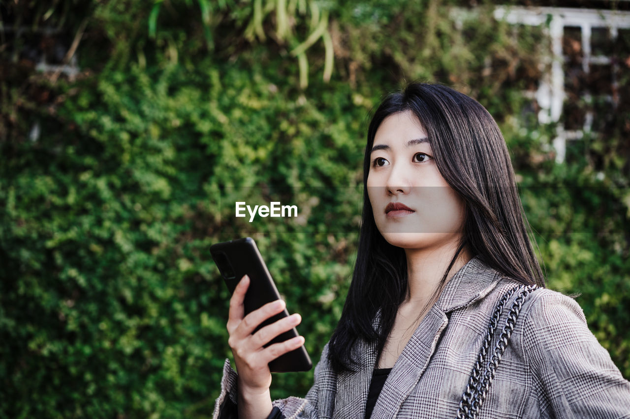 Portrait of beautiful chinese business woman using mobile phone in building office. technology