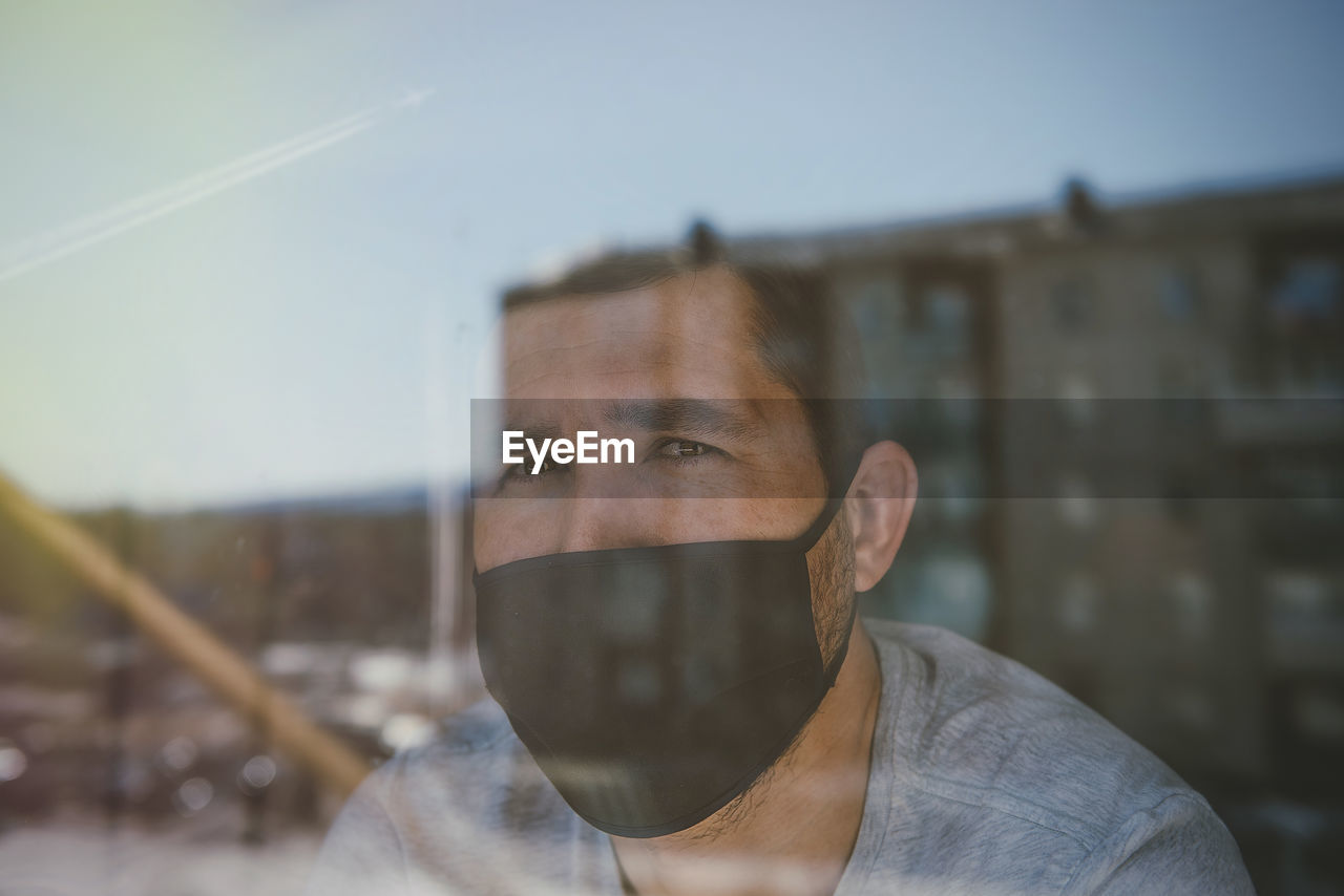 Close-up of man wearing mask seen through window