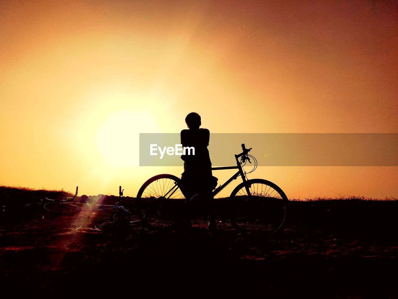 SILHOUETTE MAN RIDING BICYCLE AT SUNSET