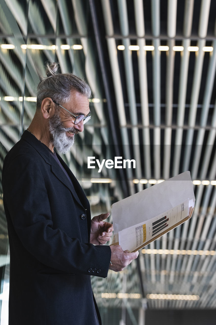 Smiling male entrepreneur reading business plan