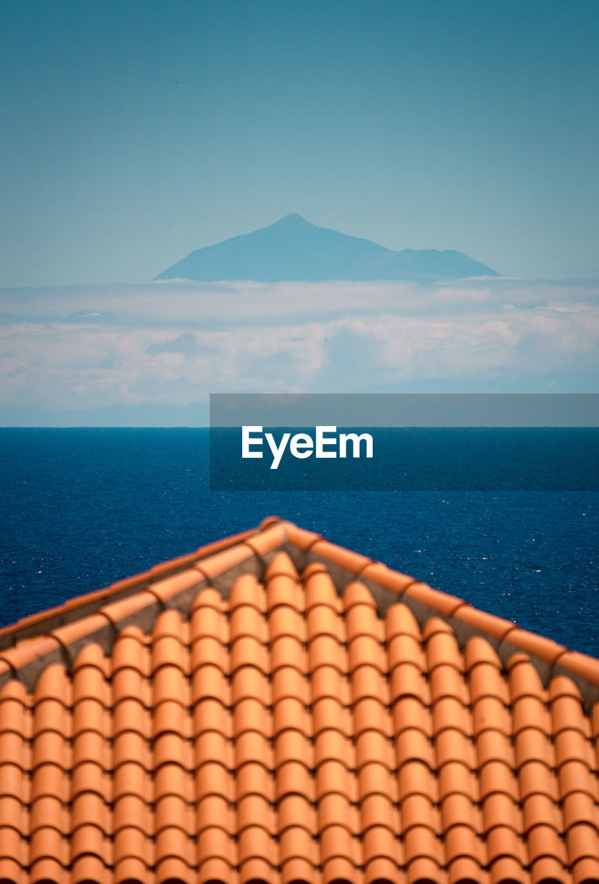 Building tile roof in a hill near ocean under blue clear sky