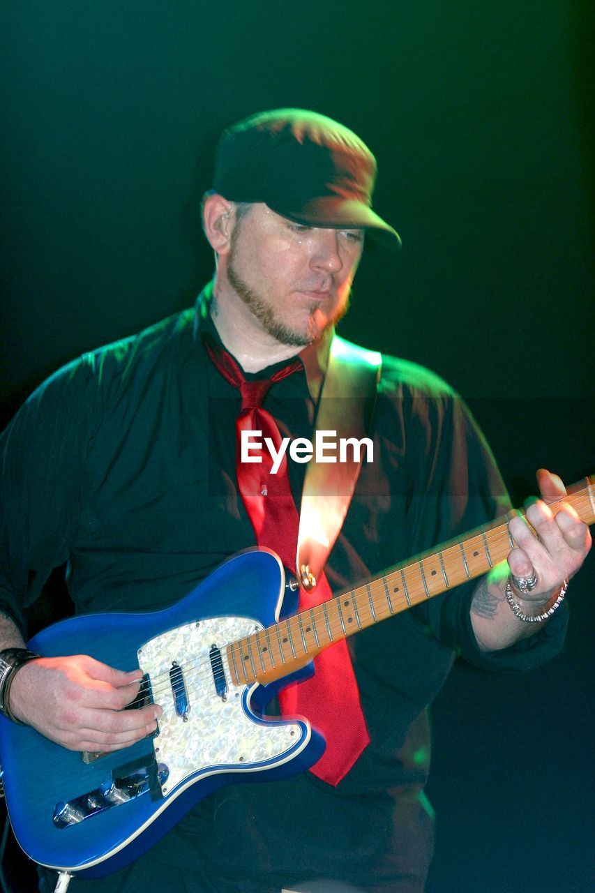 FULL LENGTH OF MAN PLAYING GUITAR ON STAGE