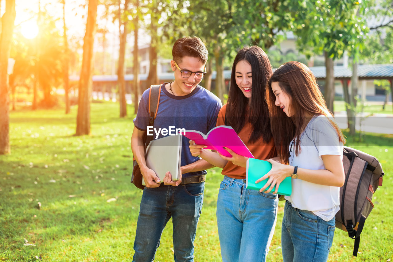 University students reading book at park