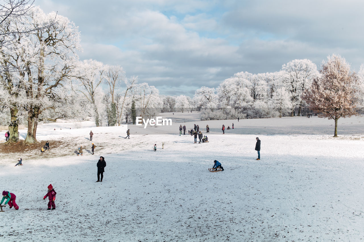 People on snow covered field against sky