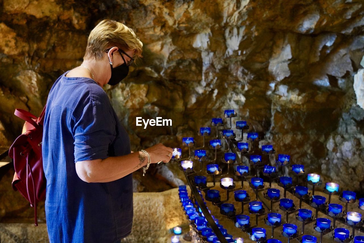 Side view of woman standing against tealight candles